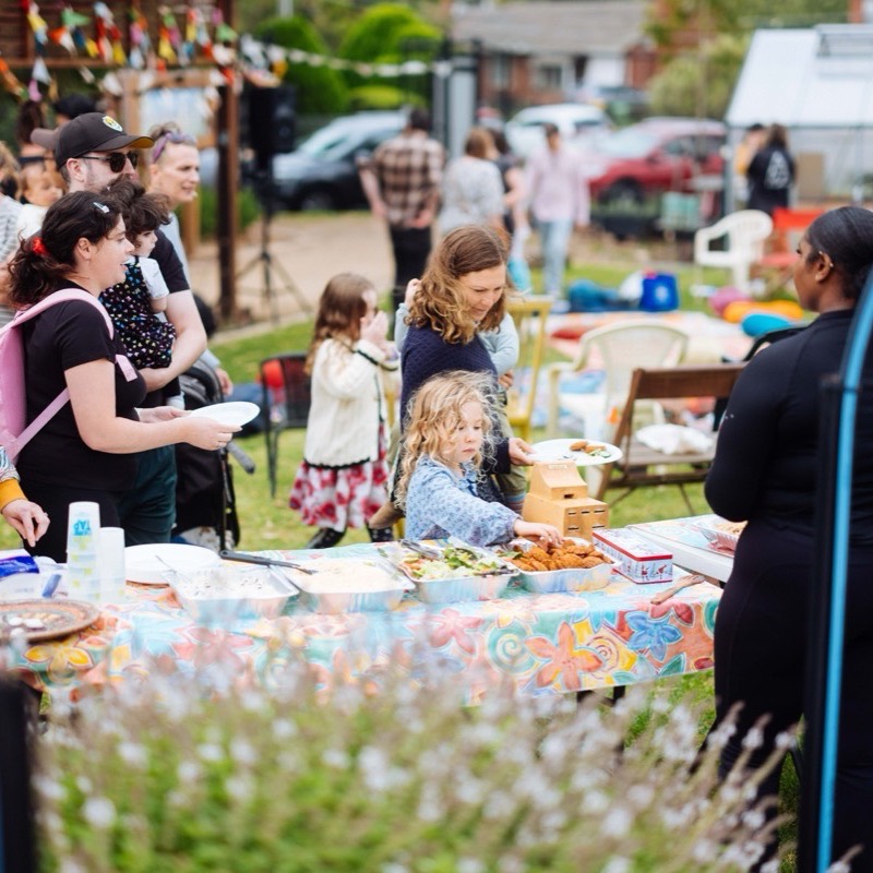Parents and children helping themselves from bowls of food at the shared table